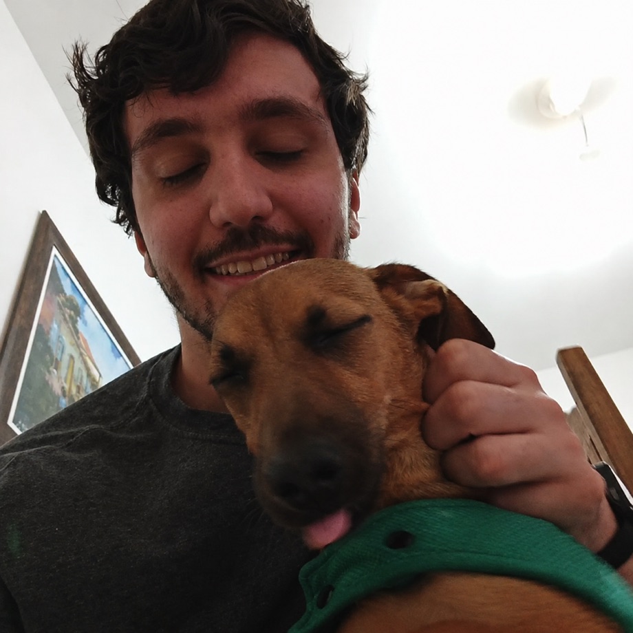 Lucas Tonon with his eyes closed, hugging the same dog